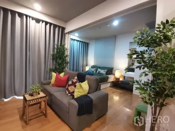 公寓 出租或出售在Watthana, Bangkok - 起居区与卧室相连，灰色窗帘与彩色抱枕沙发。