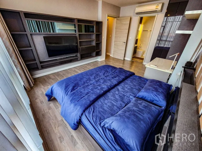 Condominium for rent or sale in Bang Rak, Bangkok - Master bedroom with built-in shelving, desk, and doorway to the ensuite.