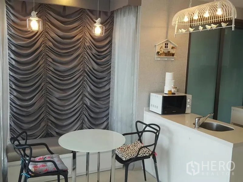 公寓 出租在Khlong Toei, Bangkok - 紧凑用餐角：圆桌、吊灯和小厨房台面。