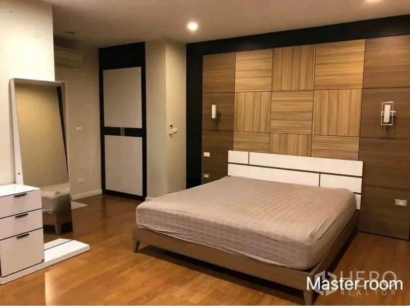 Townhouse for rent in Phra Khanong, Bangkok - Large master bedroom with accent wall, bed, freestanding mirror and wardrobe.