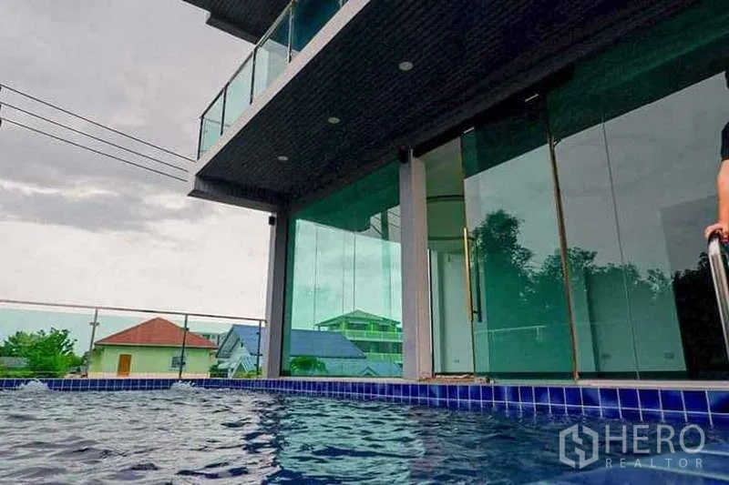 独立式住宅 出售在Lat Phrao, Bangkok - 从泳池水平视角望向住宅玻璃立面与阳台。