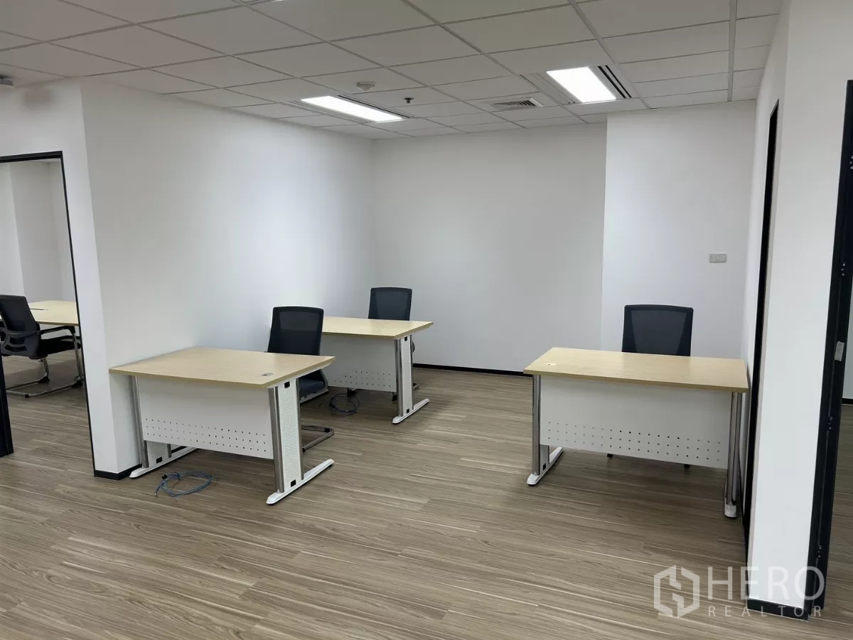 Office Space for rent - Partitioned workspace featuring three desks and office chairs under recessed lighting and wood-look floors.
