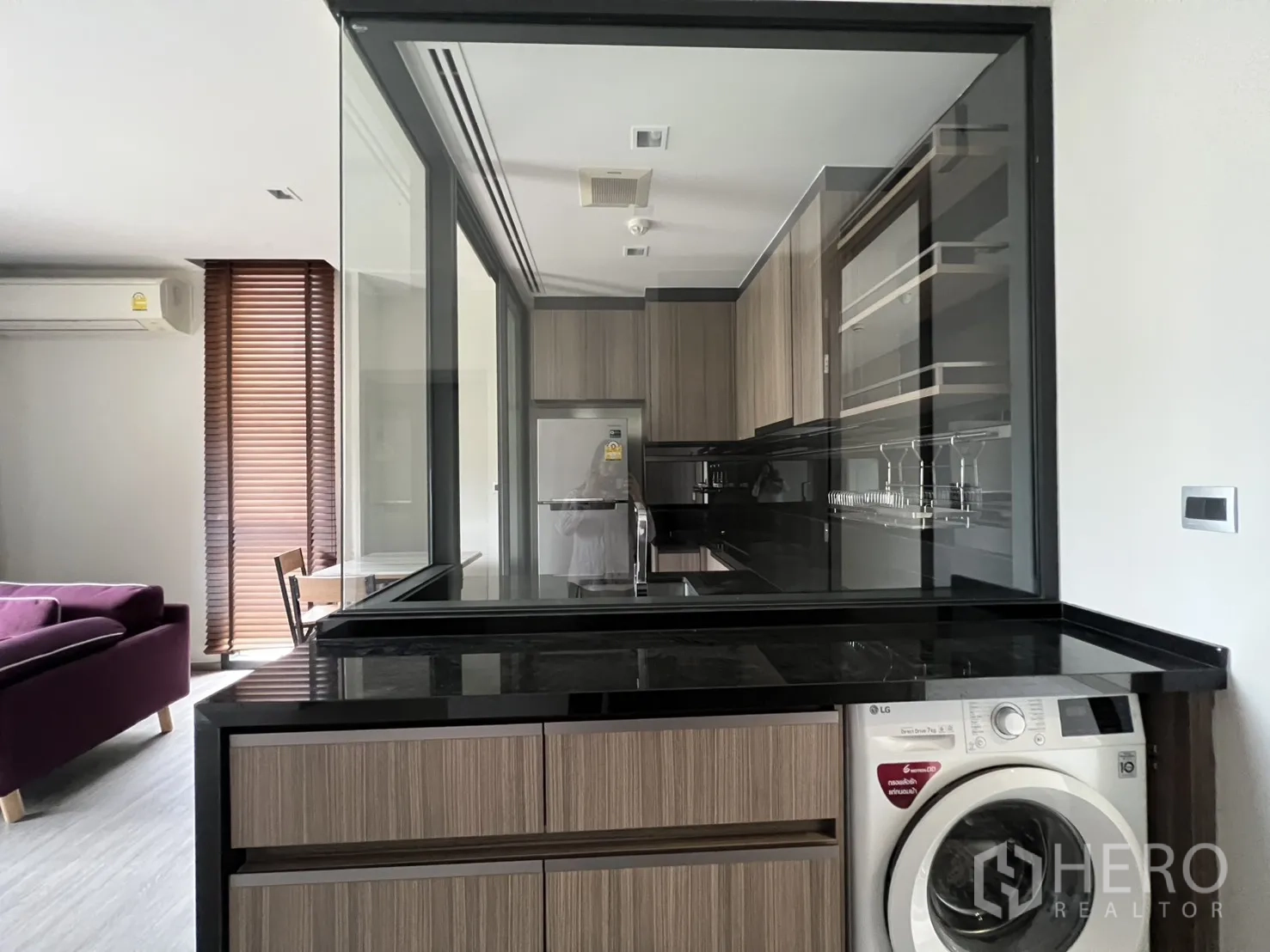 คอนโด for rent in Watthana, Bangkok - ครัวปิดกระจกมองสู่ห้องนั่งเล่นที่มีโซฟาและบานไม้บังตา