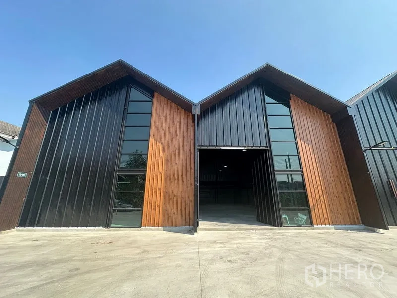 Warehouse for rent in Bueng Kum, Bangkok - Modern twin-gabled warehouse facade with black metal and wood cladding and a wide driveway in Bueng Kum.