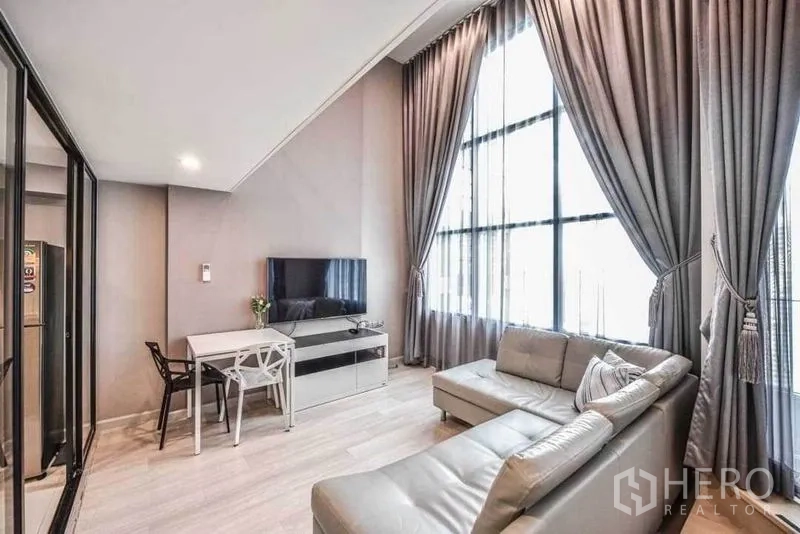 คอนโด ให้เช่าในSathon, Bangkok - ห้องนั่งเล่นสว่าง โซฟาเข้ามุม ทีวีคอนโซล และโต๊ะทานข้าว ใต้หน้าต่างสูงจรดเพดาน