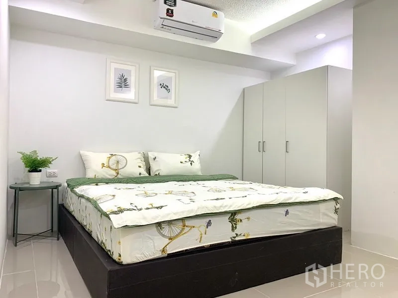 Condominium for rent or sale in Khlong Toei, Bangkok - Air-conditioned bedroom with double bed, white wardrobe and bedside table in neutral decor.