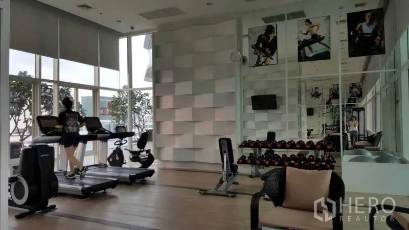 Condominium for rent in Bang Kho Laem, Bangkok - Gym with treadmills, free weights, and mirrors overlooking the city.