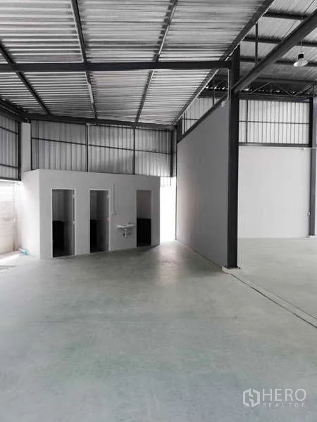 Factory for rent or sale in Ban Phaeo, Samut Sakhon - Factory interior showing a restroom block beneath the steel roof