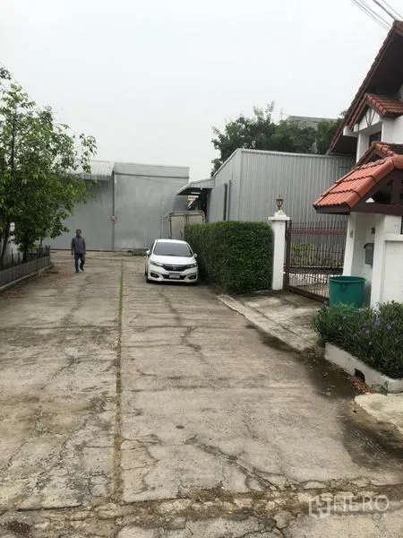 Warehouse for rent in Wang Thonglang, Bangkok - Long concrete driveway with parking area in a secure warehouse compound.