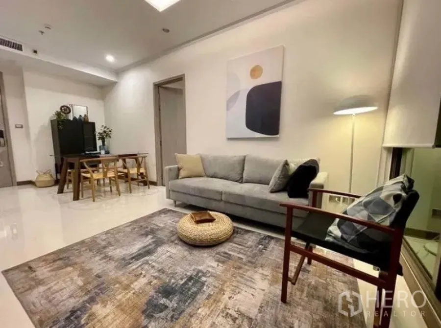 Condominium for rent in Watthana, Bangkok - Bright living room with gray sofa, armchair, area rug and floor lamp beside a dining nook.