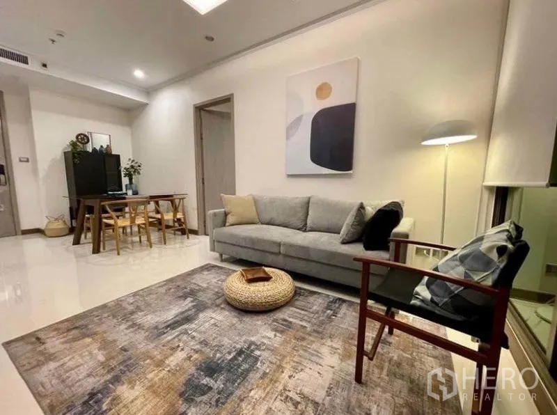 Condominium for rent in Watthana, Bangkok - Bright living room with gray sofa, armchair, area rug and floor lamp beside a dining nook.