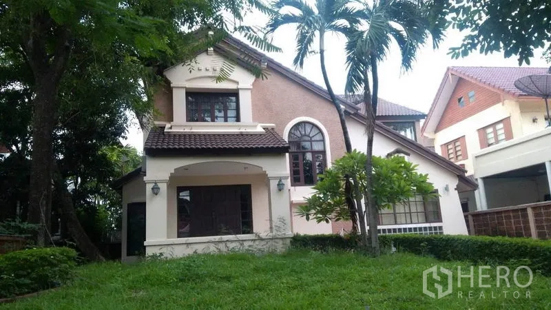 Detached House for rent - Front elevation with arched window, palm trees and grassy lawn.