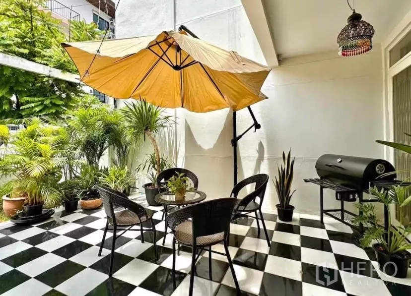 联排别墅 出租在Watthana, Bangkok - 覆盖式露台，桌椅、大遮阳伞、盆栽与烧烤炉，黑白棋盘地面