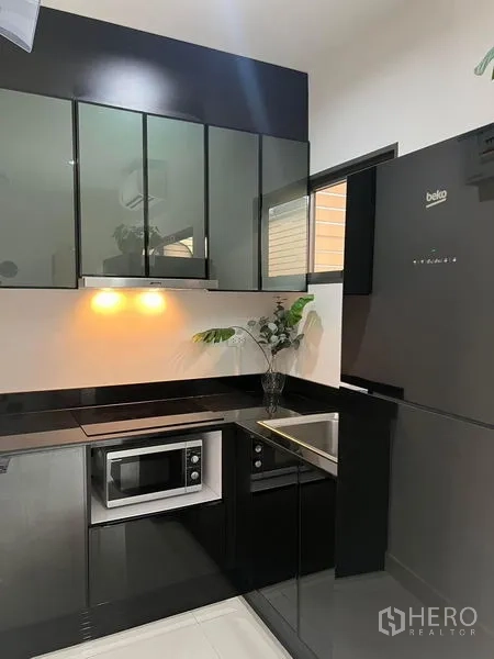 Townhouse for rent in Saphan Sung, Bangkok - Compact modern kitchen with glossy black cabinetry, built-in appliances and refrigerator.