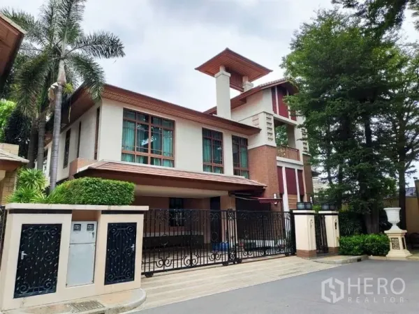 独立式住宅 出租在Watthana, Bangkok - 独栋别墅外观，带电动门与有顶车位，大窗与绿化。