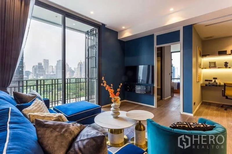 Condominium for rent in Pathum Wan, Bangkok - Living area opening to a balcony with skyline view and a dedicated work nook.