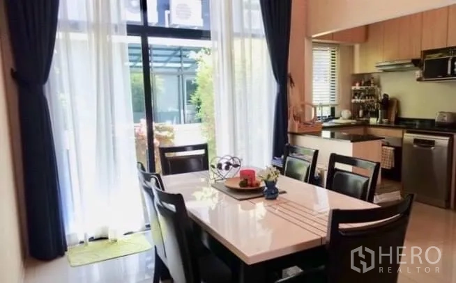 Townhouse for rent or sale in Suan Luang, Bangkok - Dining room opening to a patio through full-height sliding doors, next to the kitchen.
