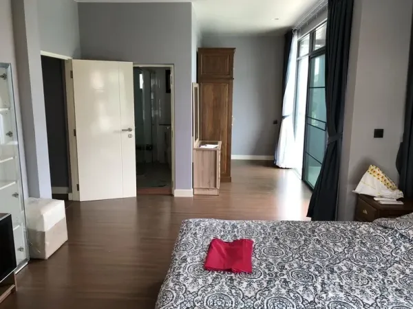 Detached House for rent in Bang Kapi, Bangkok - Spacious master bedroom with wood flooring, wardrobes, balcony-style windows and ensuite access.