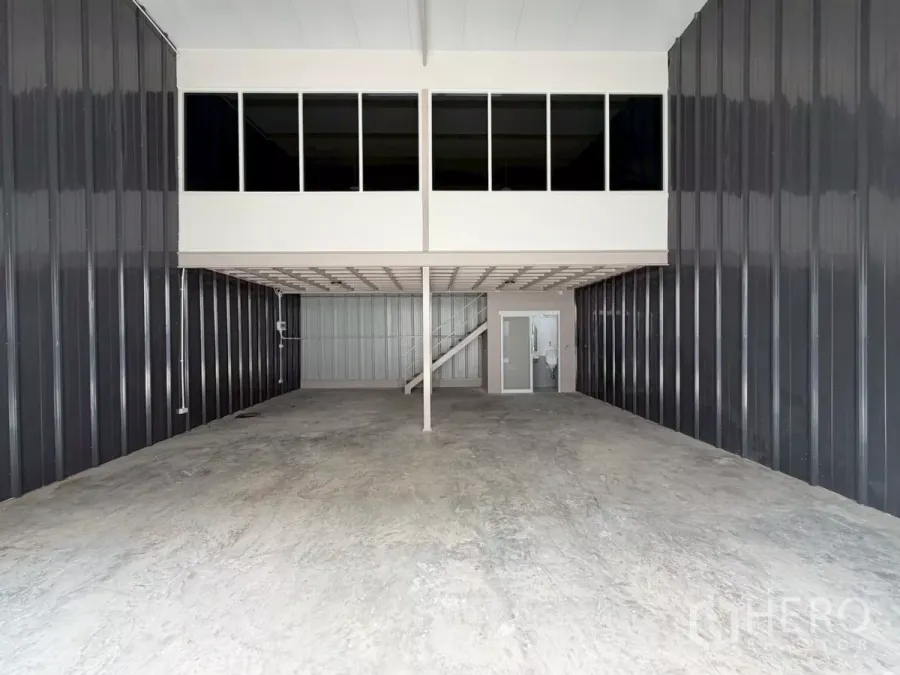 Warehouse for rent in Suan Luang, Bangkok - Spacious warehouse interior with high ceiling, mezzanine office with windows, concrete floor and roller door access.