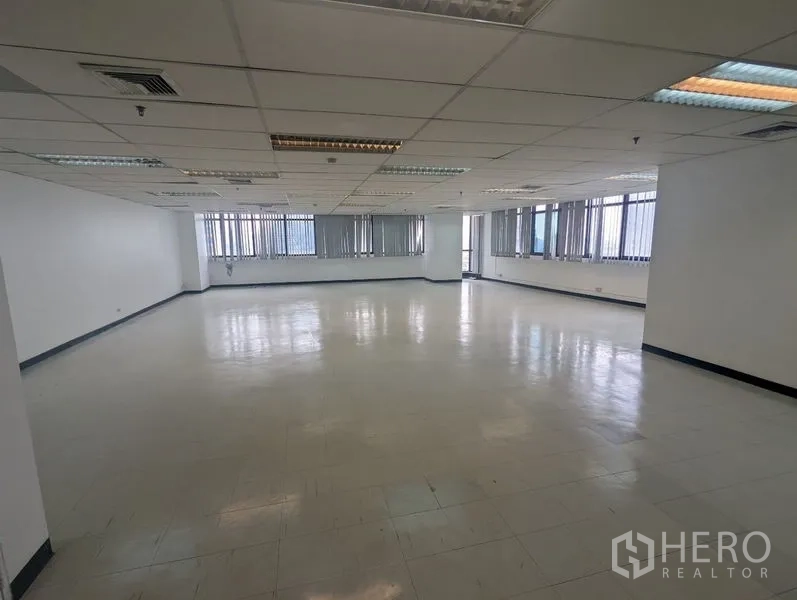 สำนักงาน ให้เช่าหรือขาย - พื้นที่สำนักงานมุมกว้าง ฝ้าเพดานตะแกรงไฟ และผนังหน้าต่างยาวติดตั้งม่านแนวตั้ง
