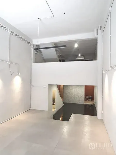 Shophouse for rent in Phra Khanong, Bangkok - Open-plan ground floor showing a mezzanine level, staircase and accent lighting in a renovated shophouse.