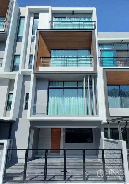 Townhouse for rent in Suan Luang, Bangkok - Modern multi-level townhouse exterior in Suan Luang with balconies, large glass panels and a gated carport.