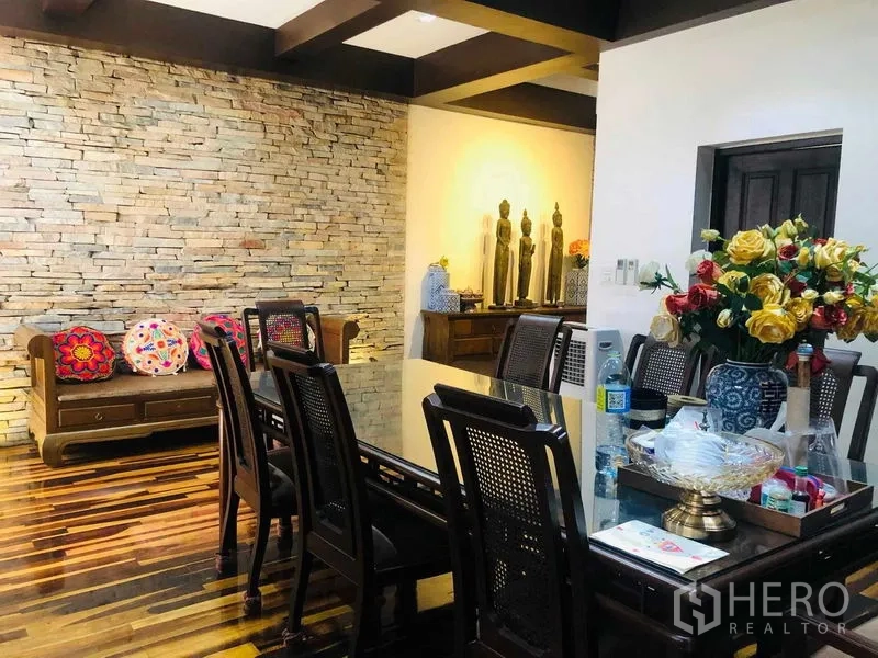Townhouse for rent in Yan Nawa, Bangkok - Dining zone with exposed ceiling beams, stone accent wall, and a wooden bench.