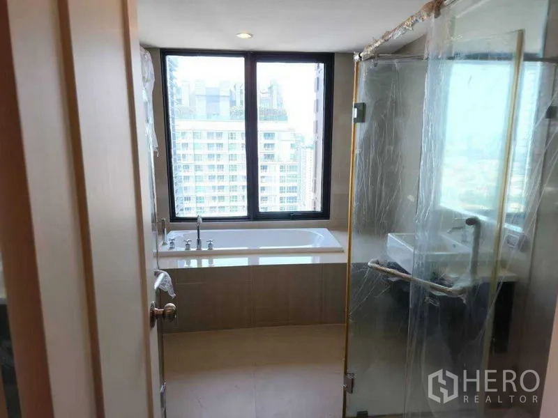 公寓 出租在Ratchathewi, Bangkok - 卫浴间配靠窗浴缸与玻璃淋浴房，可观城市景色。