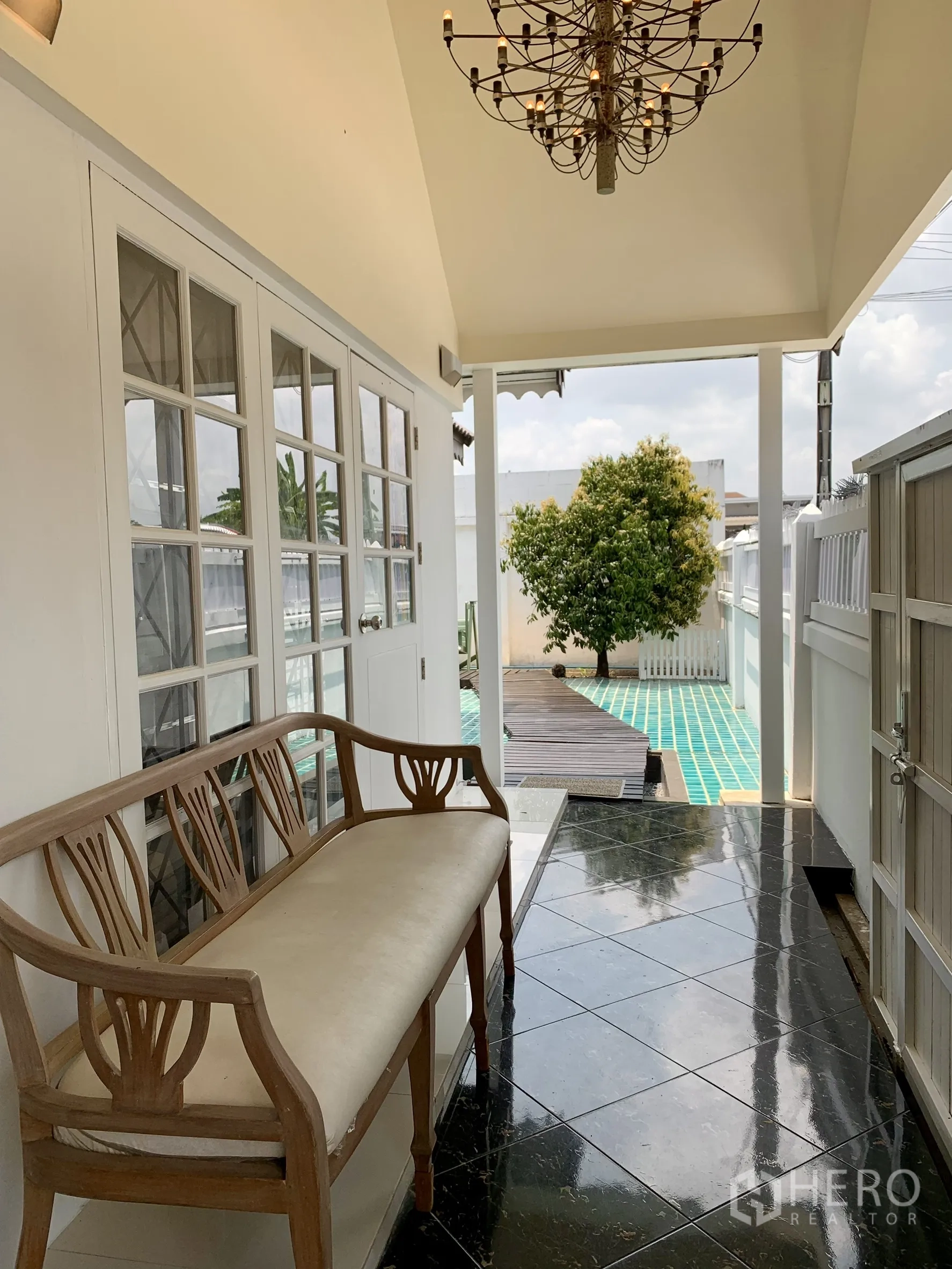 独栋房屋 for rent in Saphan Sung, Bangkok - 前廊走道一侧摆放长椅与吊灯，通向蓝绿色瓷砖露台。