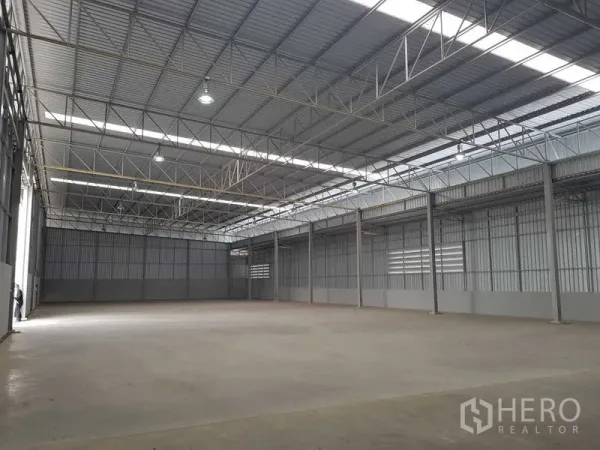 Warehouse for rent in Lat Krabang, Bangkok - Column-free warehouse bay with high-bay lights and metal cladding along the walls.