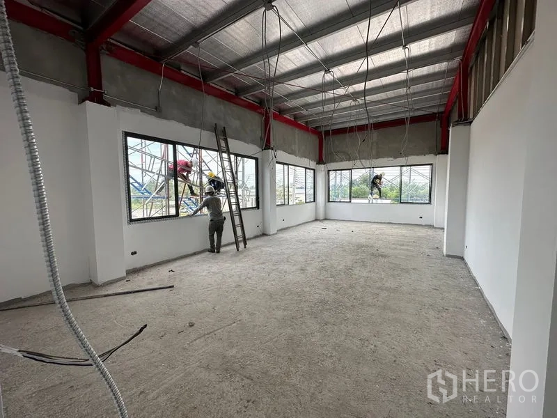 Warehouse for rent or sale in Lam Luk Ka, Pathum Thani - Corner office space with wraparound windows being installed during construction.