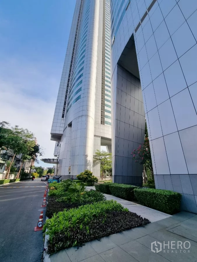 Condominium for rent in Khlong Toei, Bangkok - Exterior of modern high-rise condominium with landscaped entrance.