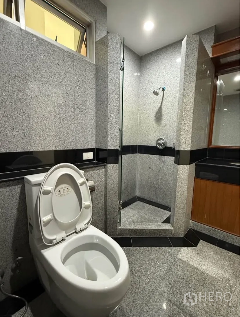 公寓 for rent in Pathum Wan, Bangkok - 带玻璃淋浴间的卫浴，花岗岩墙面，配坐便器与洗手台。