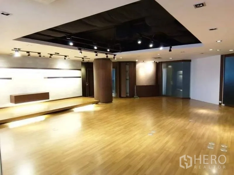 Office Space for rent - Large multipurpose room with wood flooring, small stage, spotlights and dark feature ceiling.
