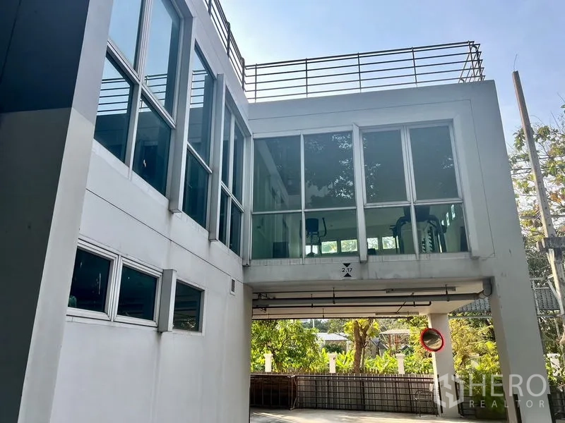 Condominium for rent in Bang Kho Laem, Bangkok - Condominium exterior featuring a glass‑walled skybridge fitness room above a landscaped area.