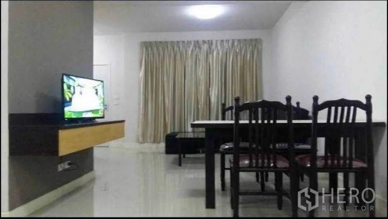 Townhouse for rent in Suan Luang, Bangkok - Open-plan living and dining area with tiled floors, curtains, TV console and dining set.