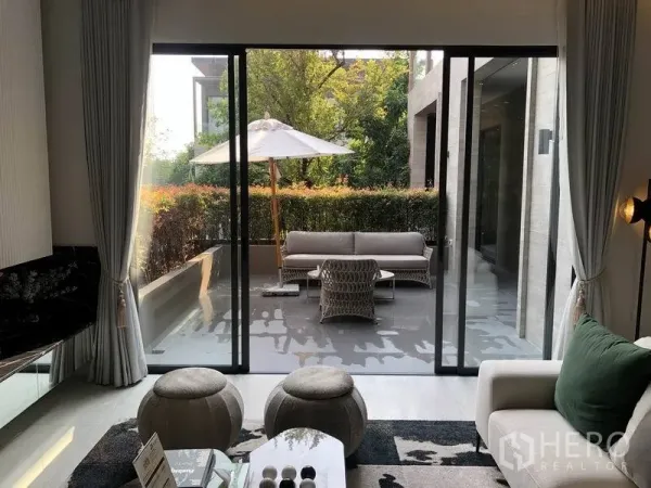 บ้าน ขายในBang Kapi, Bangkok - ห้องนั่งเล่นเปิดสู่เทอเรสมีร่มสนาม โซฟากลางแจ้ง และแนวพุ่มไม้.