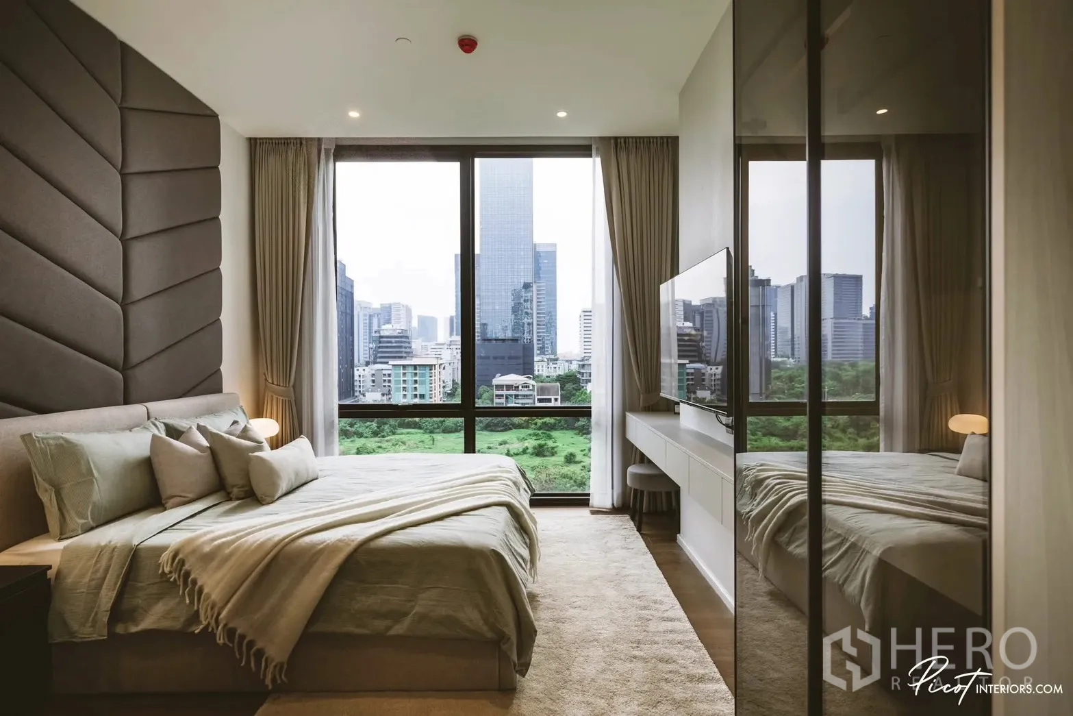 คอนโด for rent in Pathum Wan, Bangkok - ห้องนอนหลักมีหน้าต่างเต็มบาน มองเห็นสวนและสกายไลน์ ติดทีวีผนังและโต๊ะยาว