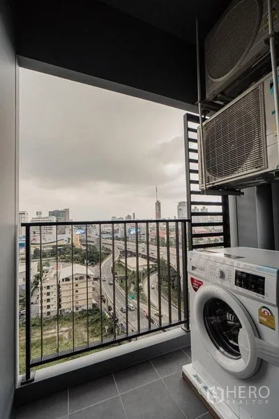 公寓 出租 - 带洗衣机与空调外机的封闭式阳台，远眺拉玛九区城市景观。