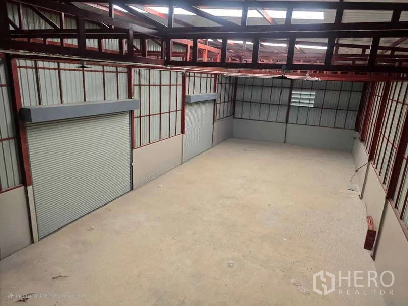 Warehouse for rent in Mueang Samut Sakhon, Samut Sakhon - Covered loading bay with three roll‑up shutter doors and red steel framing.