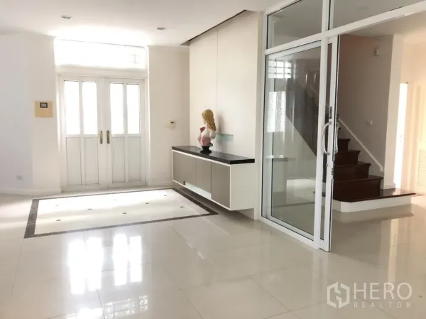 Detached House for rent or sale in Lat Phrao, Bangkok - Spacious foyer with double doors, glass sliding partition and a wooden staircase.