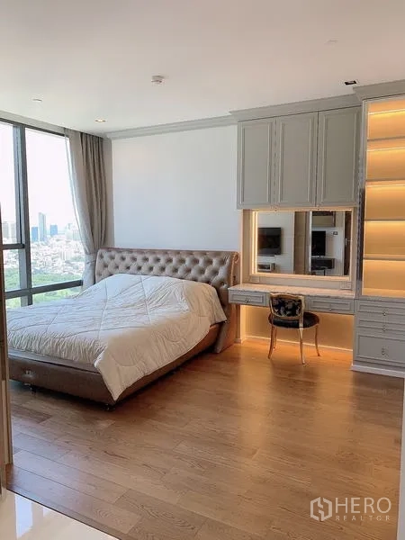 Condominium for sale - Spacious bedroom with tufted headboard, built-in vanity, and wood floors.