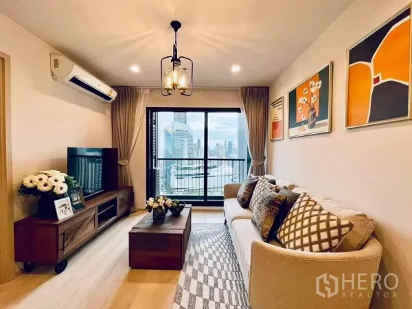 公寓 出租在Pathum Wan, Bangkok - 客厅配米色沙发、木质电视柜与吊灯，阳台可眺望曼谷天际线。