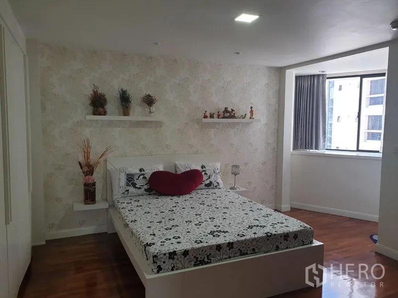 Condominium for rent in Khlong Toei, Bangkok - Bright bedroom with floral accent wall, floating shelves and large window.