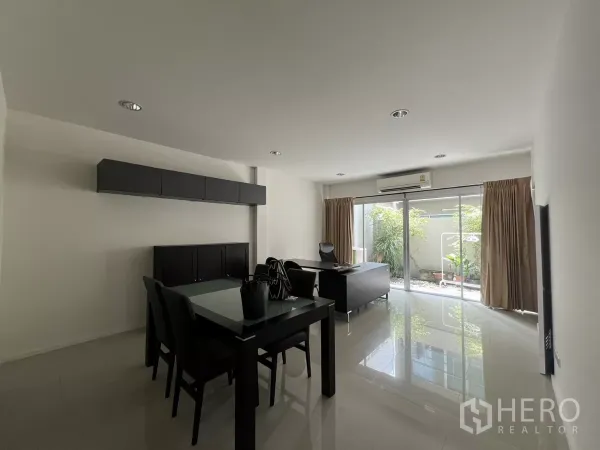 Townhouse for rent in Suan Luang, Bangkok - Dining table and work desk facing sliding doors with views of the courtyard greenery.