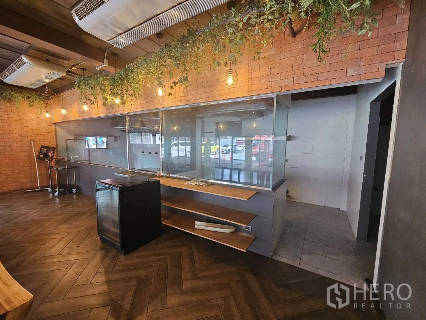 Retail Space for rent in Watthana, Bangkok - Front service counter with glass viewing panel to the kitchen, warm lighting and wood flooring.
