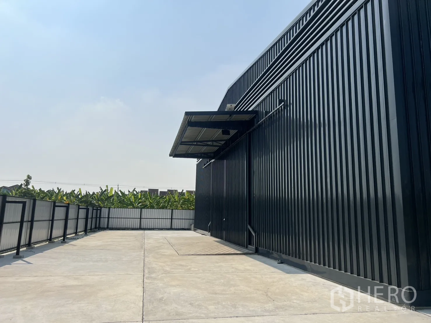 货栈 出租在Lat Krabang, Bangkok - 黑色钢结构仓库旁的围栏混凝土场地，卡车回转空间充足并设雨棚。