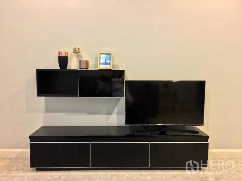 Condominium for rent in Khlong Toei, Bangkok - Media wall featuring a black TV console, mounted shelves and a flat-screen television.