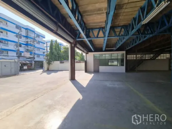 Warehouse for rent in Khlong Toei, Bangkok - Loading bay with open roller doors, blue beams and a glass-walled office.