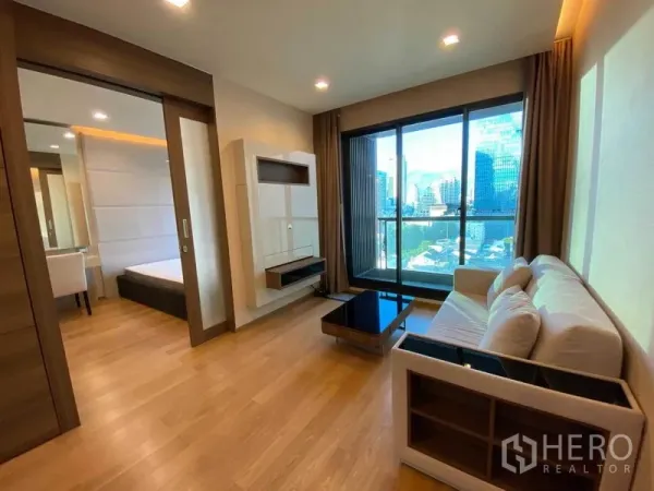 คอนโด ให้เช่าในBang Rak, Bangkok - ห้องนั่งเล่นตู้ทีวีติดผนัง ประตูบานเลื่อนเข้าห้องนอน และวิวเมือง